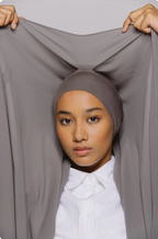 Person wearing a gray hijab with a plain background