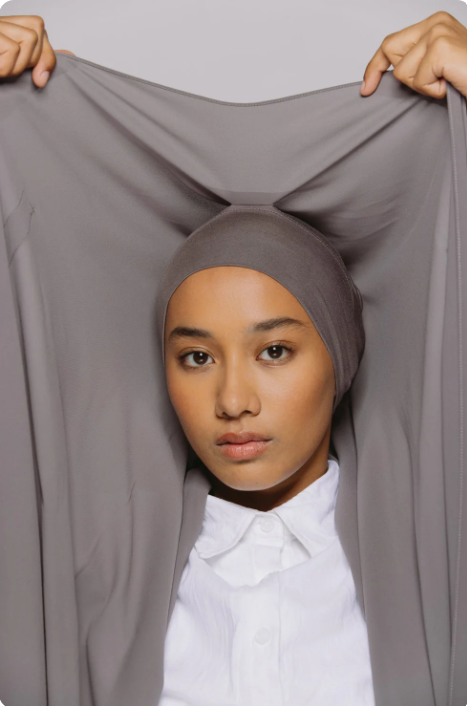 Person wearing a gray hijab with a plain background