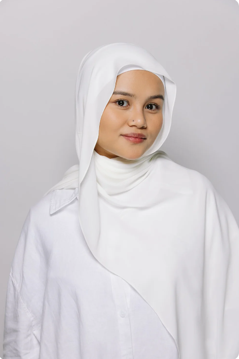 Woman wearing a white hijab and white outfit against a light gray background